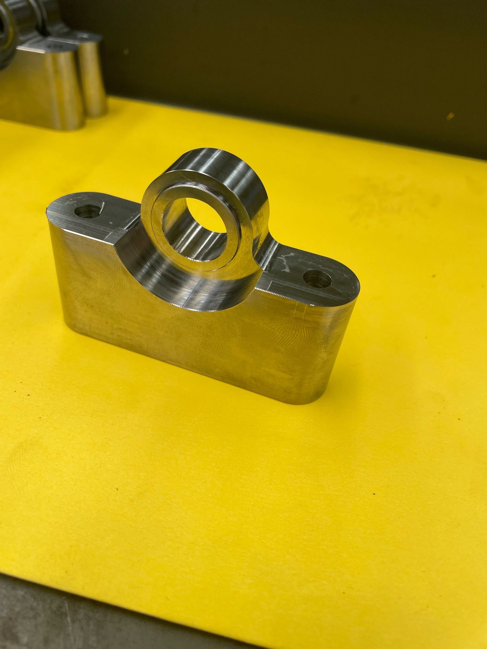 Polished steel saddle bracket with central bore, CNC milling Padco Engineering