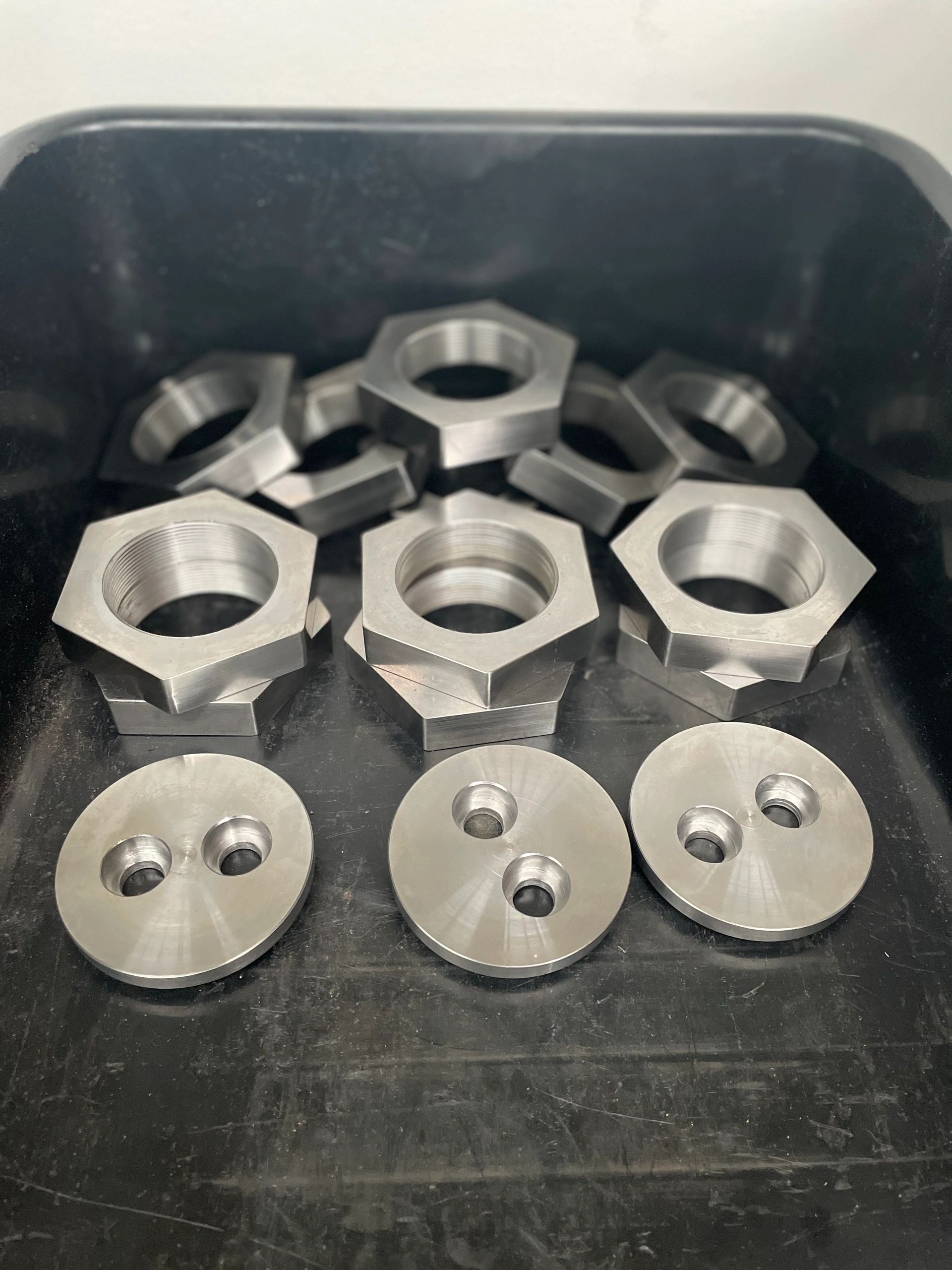 Production batch of hex nuts and round flange caps in parts tub