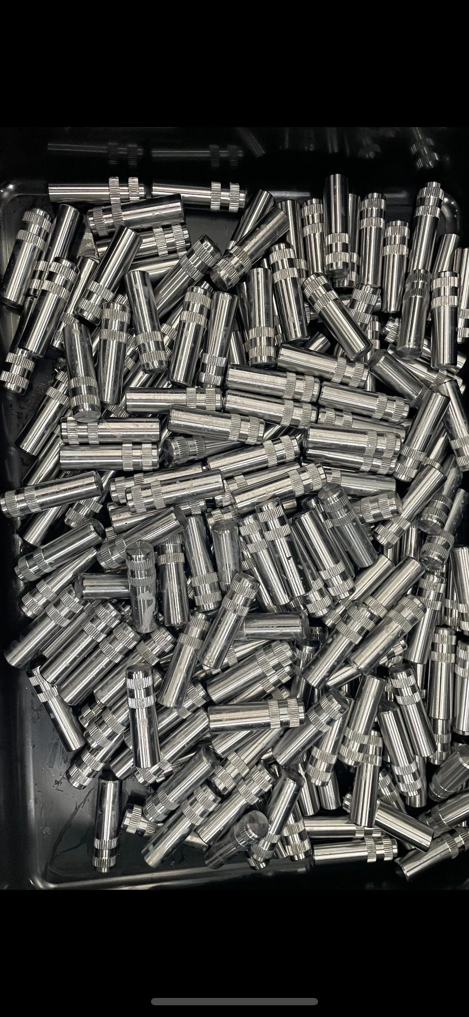 Bin of knurled stainless machined pins, production volume