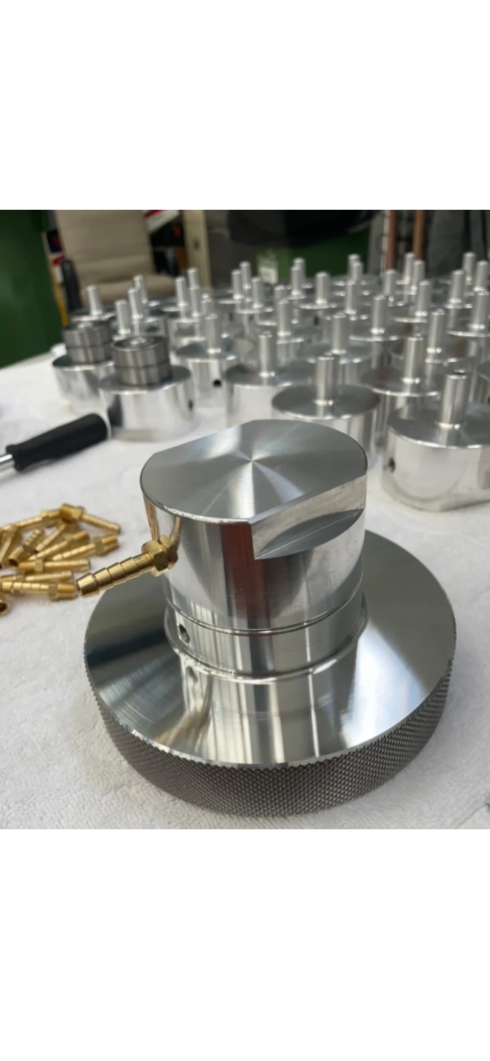 Knurled aluminium component with production batch in background
